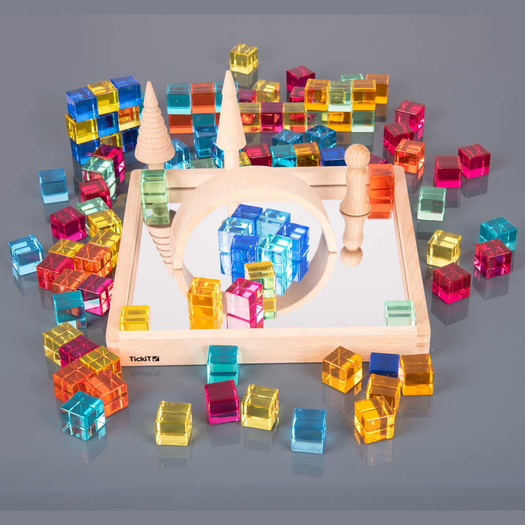 A square wooden tray with a mirrored base and colorful gem-like insets, designed to inspire sensory exploration, pattern making, and visual play.
