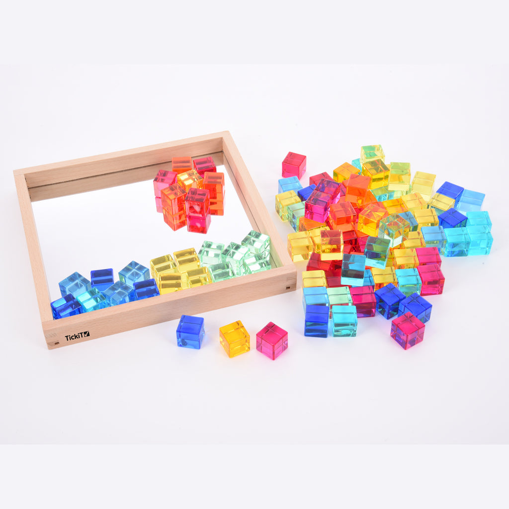 A square wooden tray with a mirrored base and colorful gem-like insets, designed to inspire sensory exploration, pattern making, and visual play.