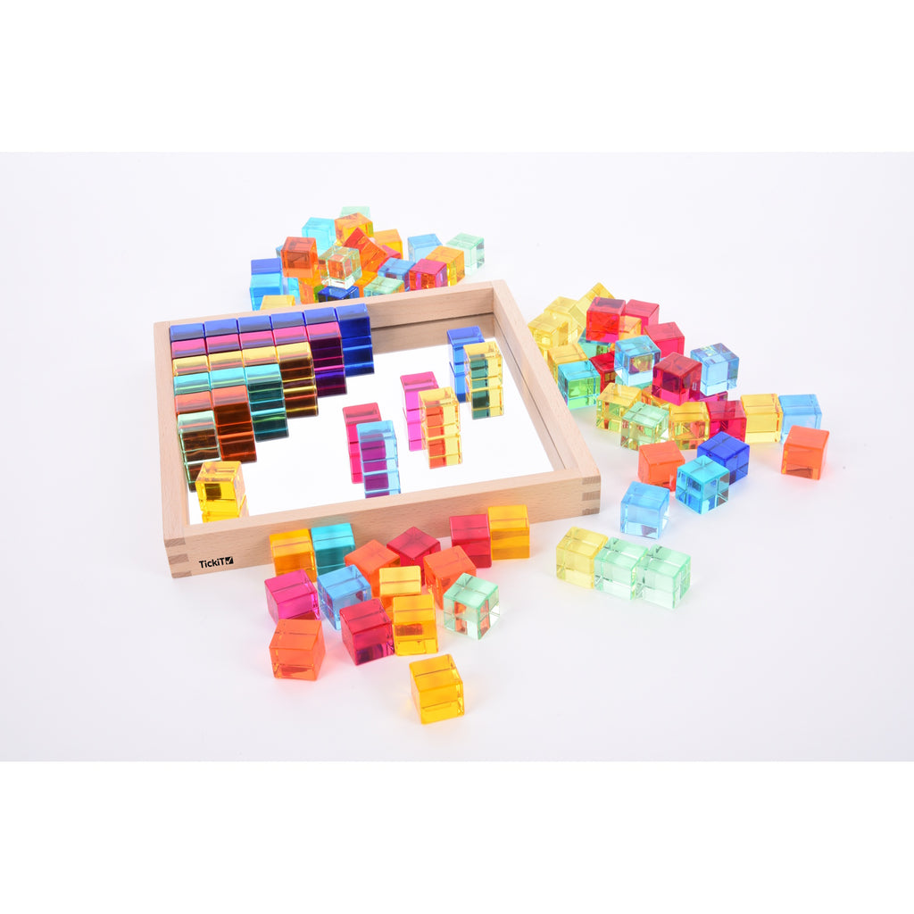 A square wooden tray with a mirrored base and colorful gem-like insets, designed to inspire sensory exploration, pattern making, and visual play.