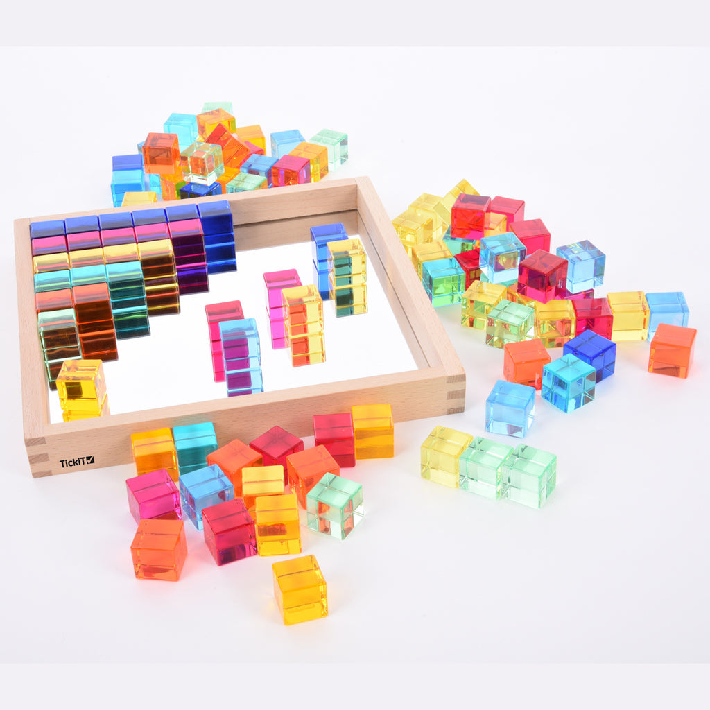 A square wooden tray with a mirrored base and colorful gem-like insets, designed to inspire sensory exploration, pattern making, and visual play.