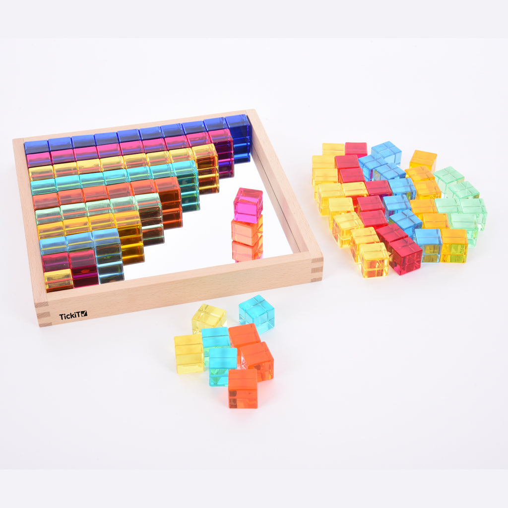 A square wooden tray with a mirrored base and colorful gem-like insets, designed to inspire sensory exploration, pattern making, and visual play.