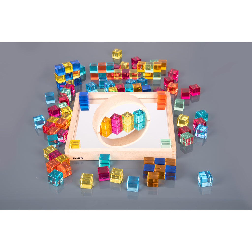 A square wooden tray with a mirrored base and colorful gem-like insets, designed to inspire sensory exploration, pattern making, and visual play.