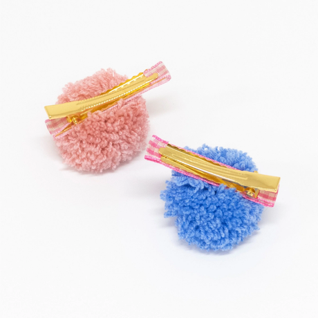 Backs of two pom-pom hair clips showing gold metal alligator clips on gingham ribbons.