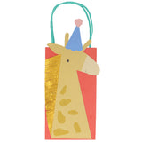 Meri Meri animal parade giraffe party bag with gold fringe mane and blue party hat on a red paper gift bag with handles.
