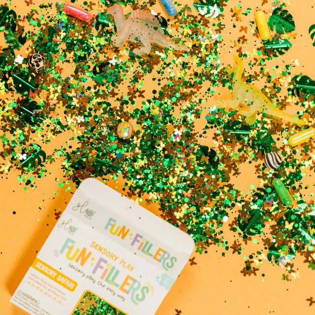 Glo Pals Sensory Safari Fun Fillers box on a yellow background with green leaf confetti and animal trinkets.