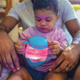 Child holding a light-up blue Glo Pals Mini Sensory Play Jar glowing with pink light.