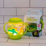Glowing green Glo Pals Mini Sensory Play Jar with floating shapes, set next to its retail box.