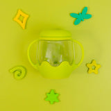 Green sensory jar with two handles, surrounded by colorful plastic shapes on a bright green background.