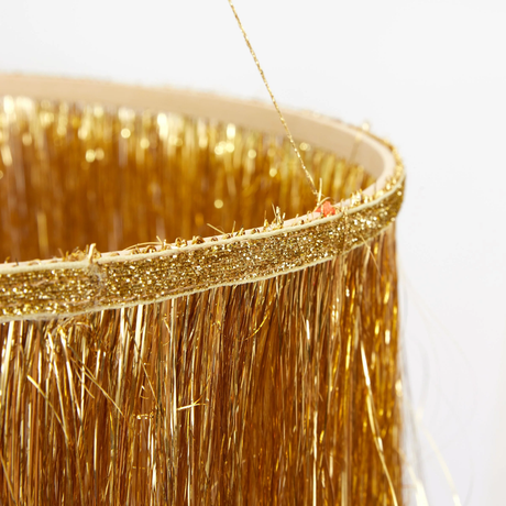 Close-up detail of the gold glitter ribbon band and metallic tinsel fringe on a hanging chandelier decor.