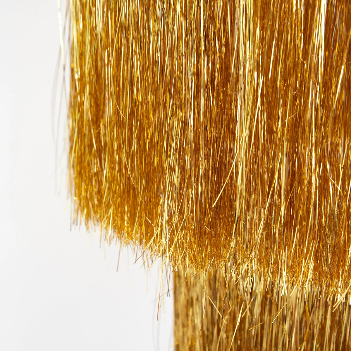 Close-up detail of the metallic gold tinsel fringe layers on a hanging party chandelier.