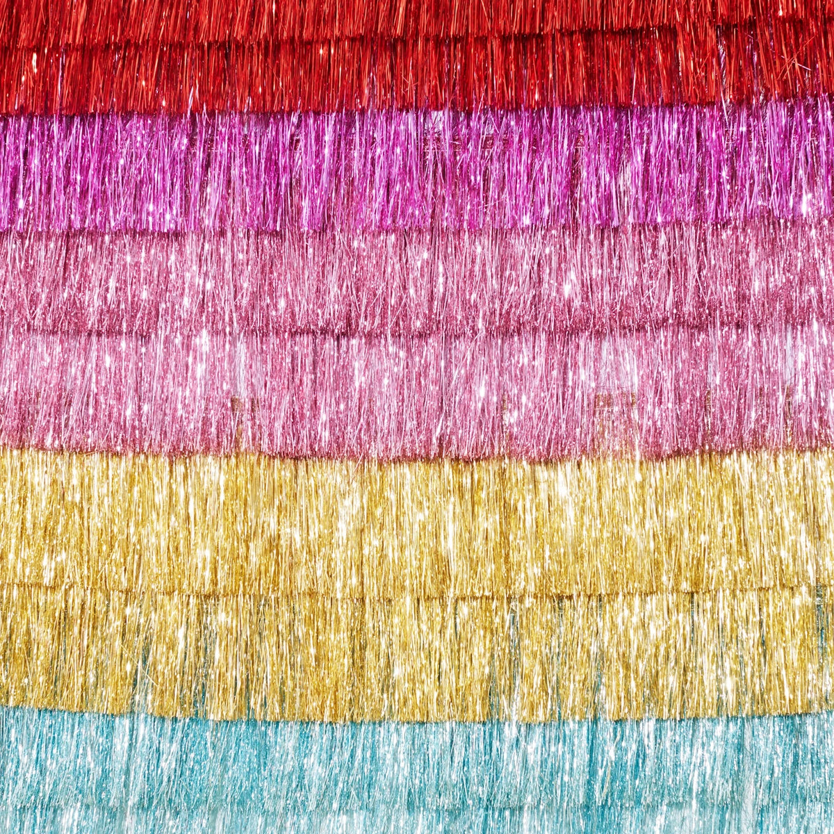 Multi-colored tinsel fringe backdrop featuring layered rows in red, magenta, pink, gold, and light blue.