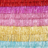 Multi-colored tinsel fringe backdrop featuring layered rows in red, magenta, pink, gold, and light blue.
