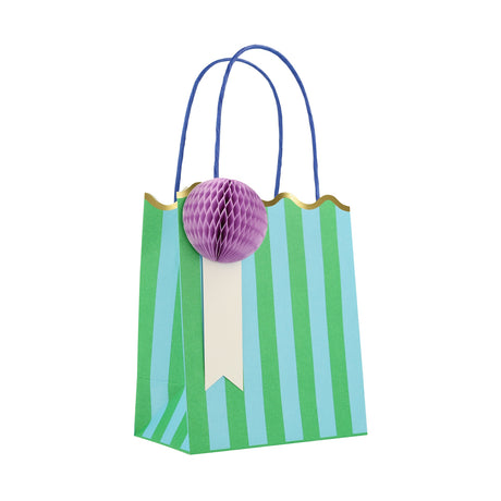 Meri Meri striped party bag with blue and green stripes, blue handles, and a purple honeycomb paper pom-pom embellishment.