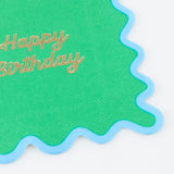 A green wavy napkin with a light blue border and "Happy Birthday" written in gold script.