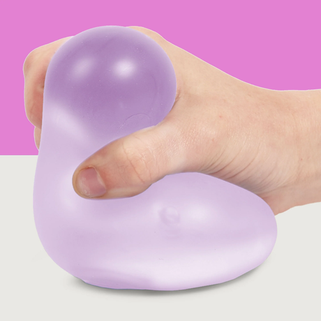 A hand squeezes a soft, purple stress ball against a two-tone background, with pink on top and white below. The scene conveys relaxation and calm.