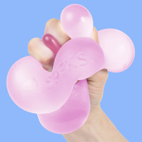 A hand is squeezing a pink, balloon-like stress ball marked "SPEKS" against a light blue background. The scene conveys a playful and tactile sensation.