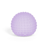 A lavender, textured massage ball with a dimpled surface, set against a plain white background. The soft hue conveys a calming, therapeutic vibe.