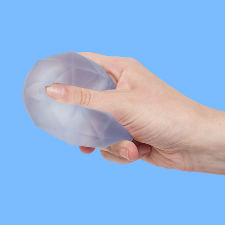 A hand squeezing a translucent, textured stress ball against a solid blue background. The image conveys a sense of tension release.