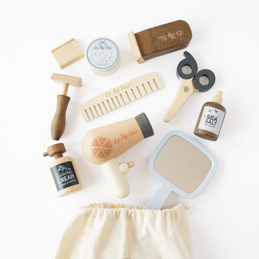 Toy barber set featuring a fabric bag, wooden styling tools, a comb, mirror, and play hair products. The set conveys a playful, vintage barber theme.