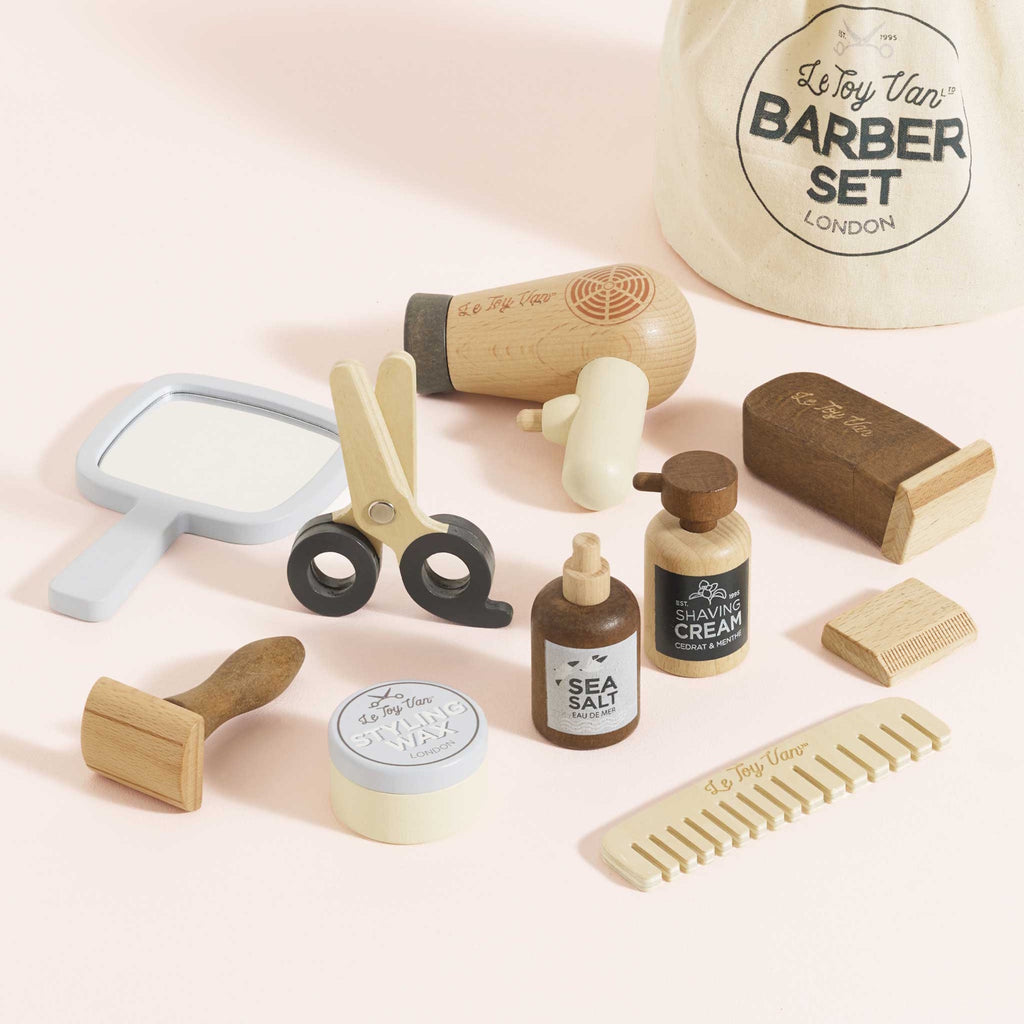 Toy barber set featuring wooden styling tools, a comb, mirror, and play hair products. The set conveys a playful, vintage barber theme.