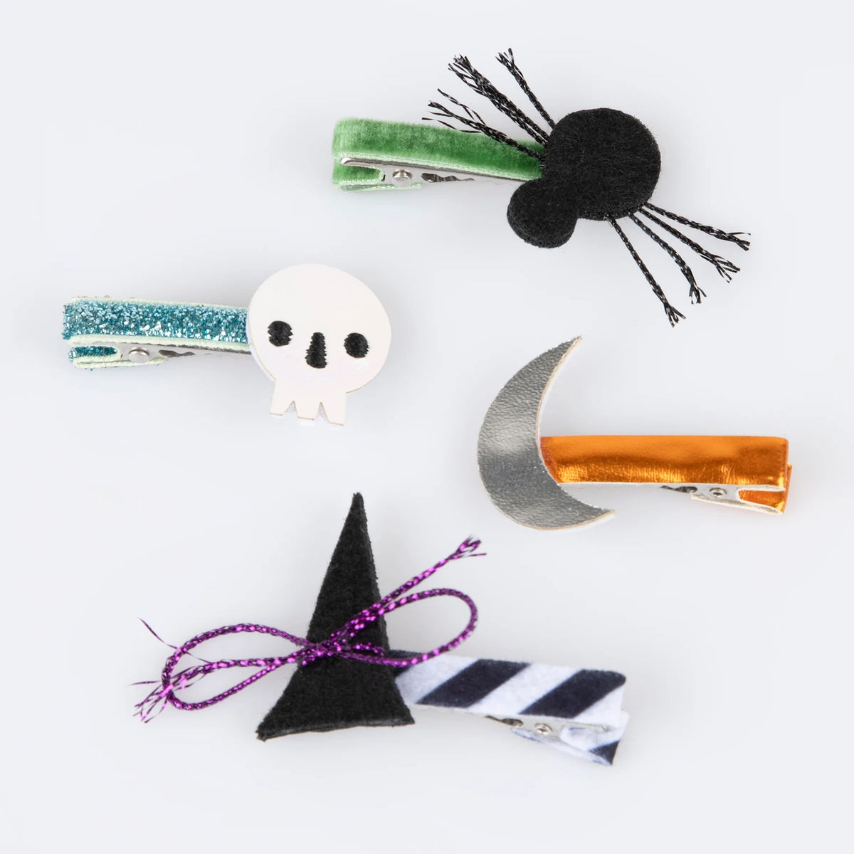 Four Halloween hair clips including a black spider, white skull, silver moon, and witch hat.