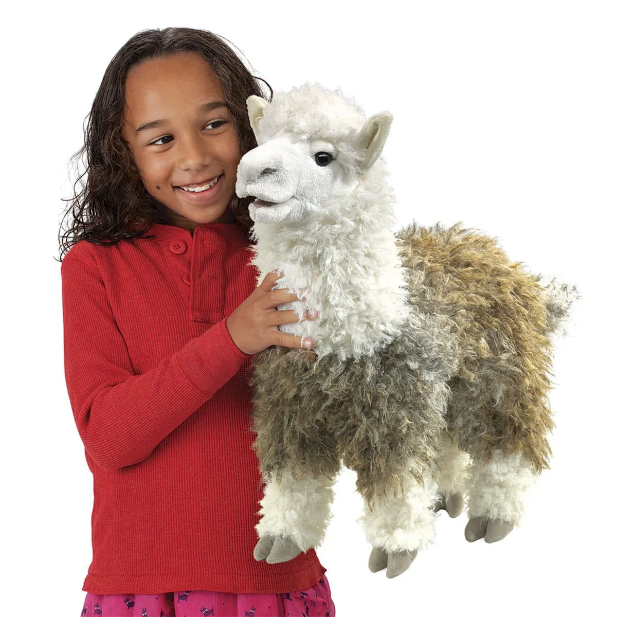 A young smiling girl holding a fluffy white and brown alpaca hand puppet.