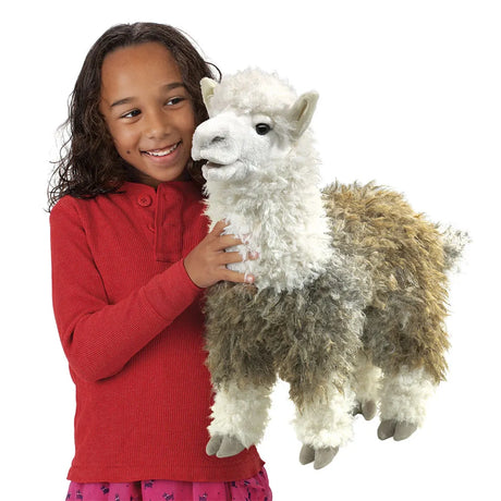 A young smiling girl holding a fluffy white and brown alpaca hand puppet.