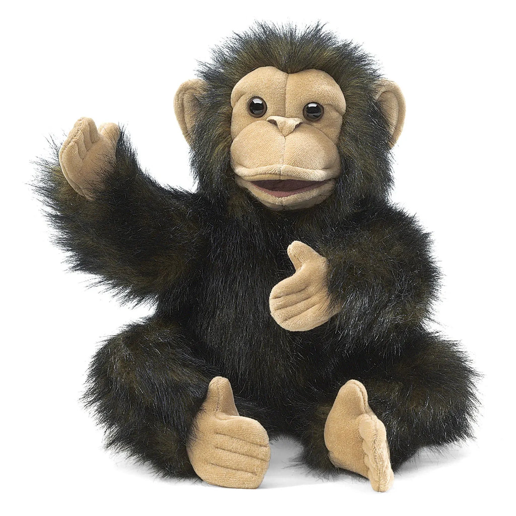 A plush monkey puppet with black fur and tan face, hands, and feet, sits with its arms raised. Its expression is playful and inviting.
