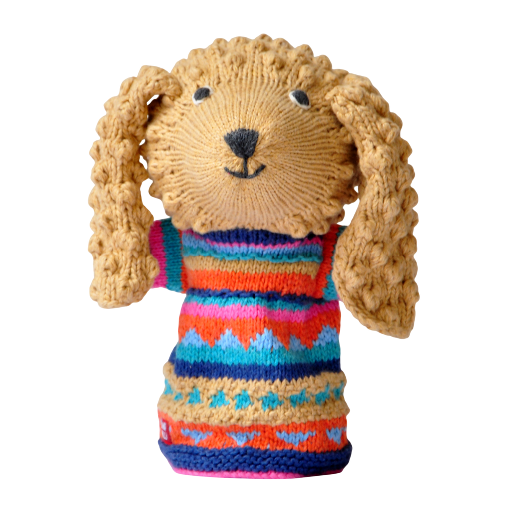 Knitted dog puppet with curly ears, wears a colorful sweater with geometric patterns in orange, blue, pink, and teal, set against a white background.