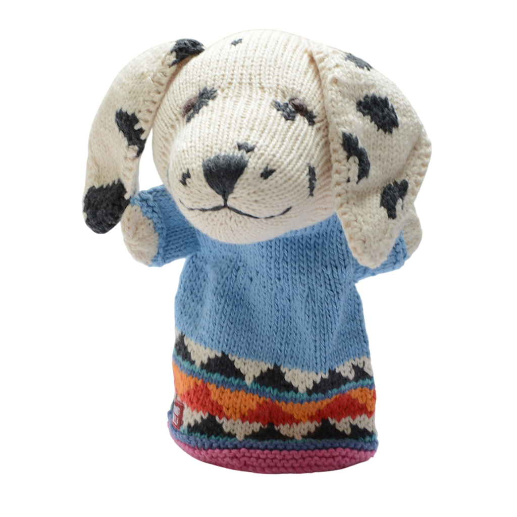 A knitted dog puppet with floppy, spotted ears wears a light blue sweater. The hem features colorful zigzag patterns, set against a white background.