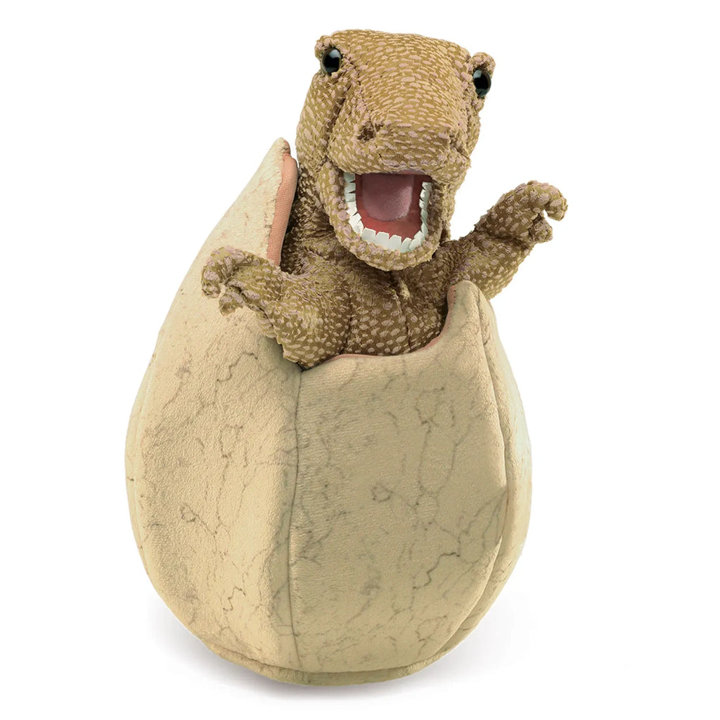 A textured dinosaur toy hatches from a cracked egg, showing its open mouth and tiny arms. The scene is playful and vivid, capturing curiosity.