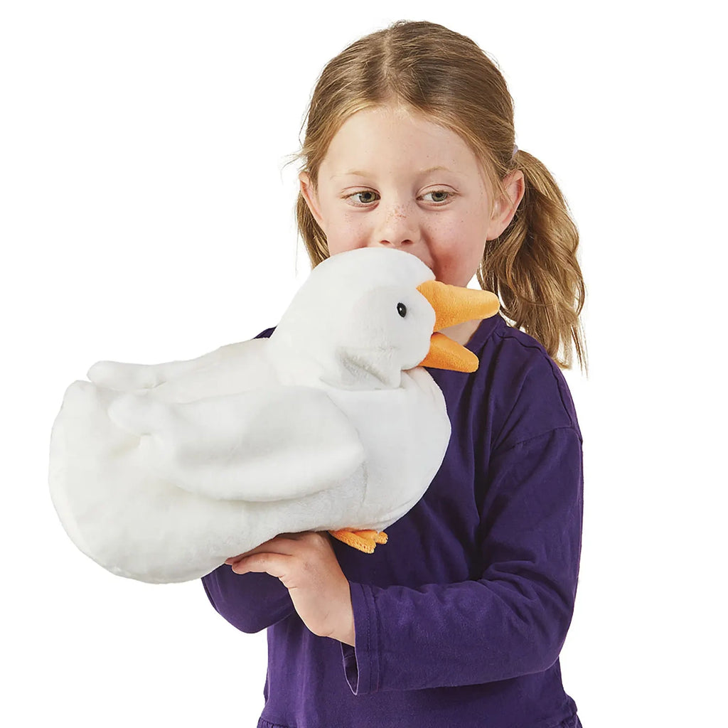 A young child in a purple shirt joyfully holds a large white duck plush toy. The child appears happy and playful, with a gentle smile on their face.