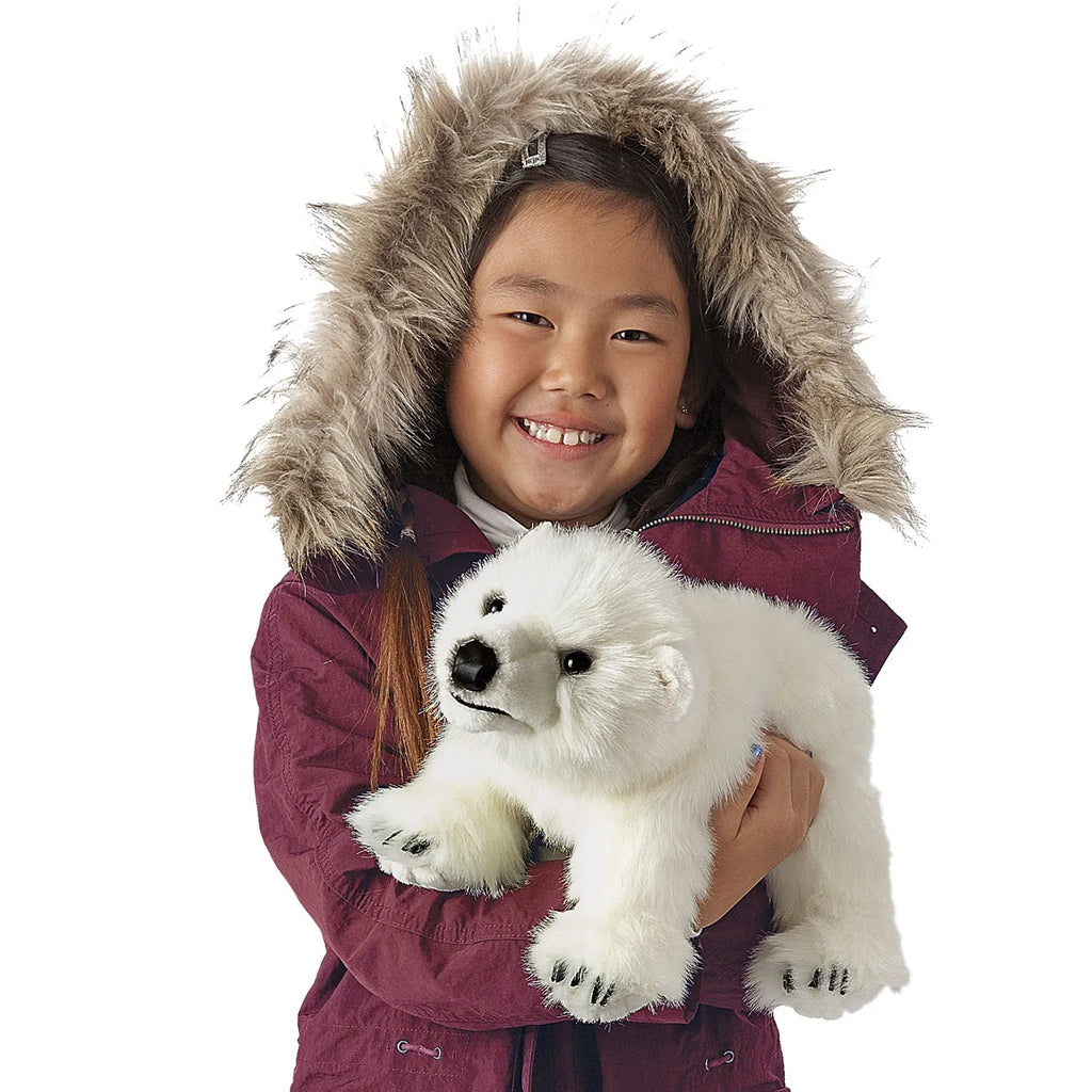 Smiling child in a fur-trimmed parka holds a plush polar bear toy, conveying warmth and joy. The coat is maroon, and the polar bear is fluffy and white.