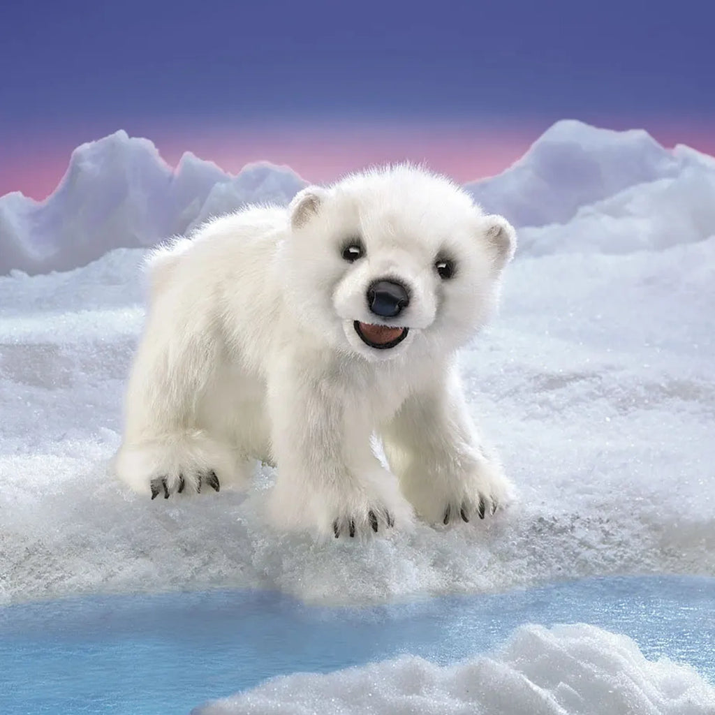 A cheerful polar bear cub stands on a snowy landscape with icy peaks under a purple and pink sky. The cub looks playful and curious.