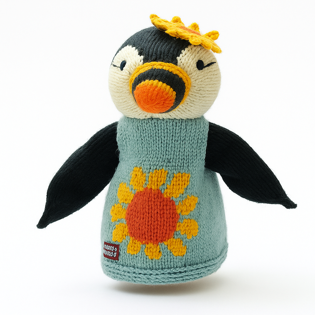 Knitted penguin hand puppet with a yellow flower on its head and a sunflower on its turquoise sweater. It has an orange beak and wings spread wide.