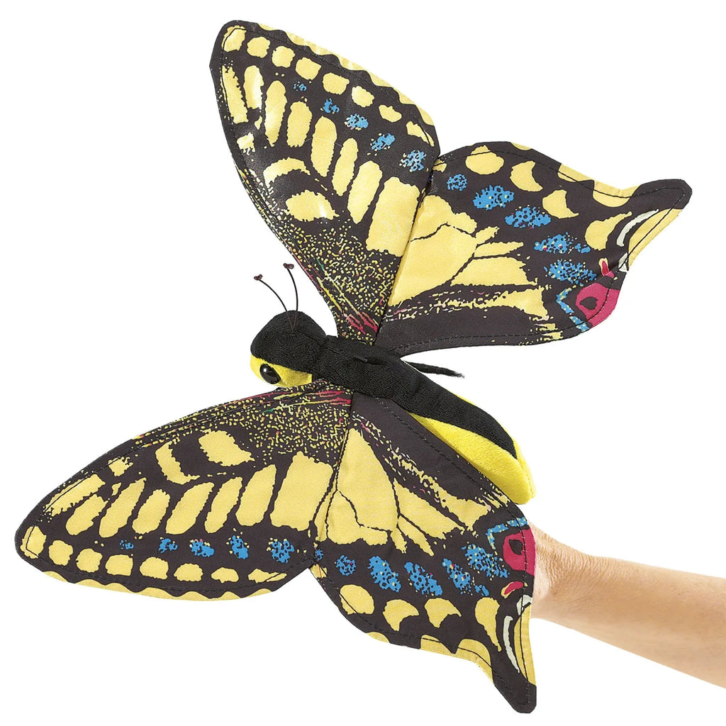 A hand holds a lifelike butterfly puppet with vibrant yellow, black, and blue wings, conveying a sense of whimsy and creativity. The bright colors stand out.