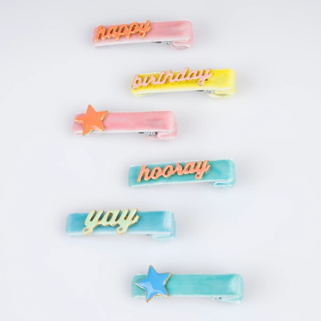 Six colorful velvet hair clips with star charms and text like "happy", "birthday", "hooray", and "yay".
