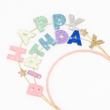 Close-up view of the Meri Meri glitter headband spelling "Happy Birthday" with colorful letters and small star accents.