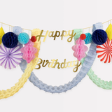 Close-up of a Happy Birthday garland with gold script letters surrounded by tissue fans and honeycomb shapes.