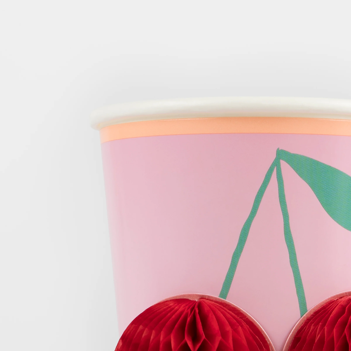 Close-up of a pink Meri Meri party cup highlighting the texture of the 3D red honeycomb cherry design.