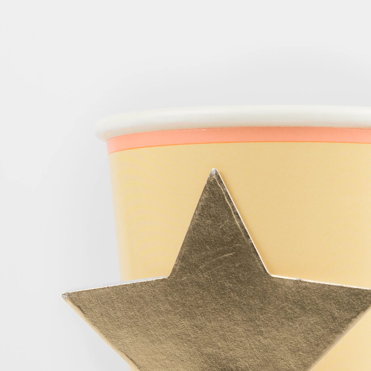 Close-up of a yellow Meri Meri party cup highlighting the texture and detail of the gold foil star design.