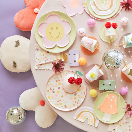 Overhead view of a colorful party table setup with Meri Meri tableware, plates, napkins, 3D honeycomb cups, and disco balls.