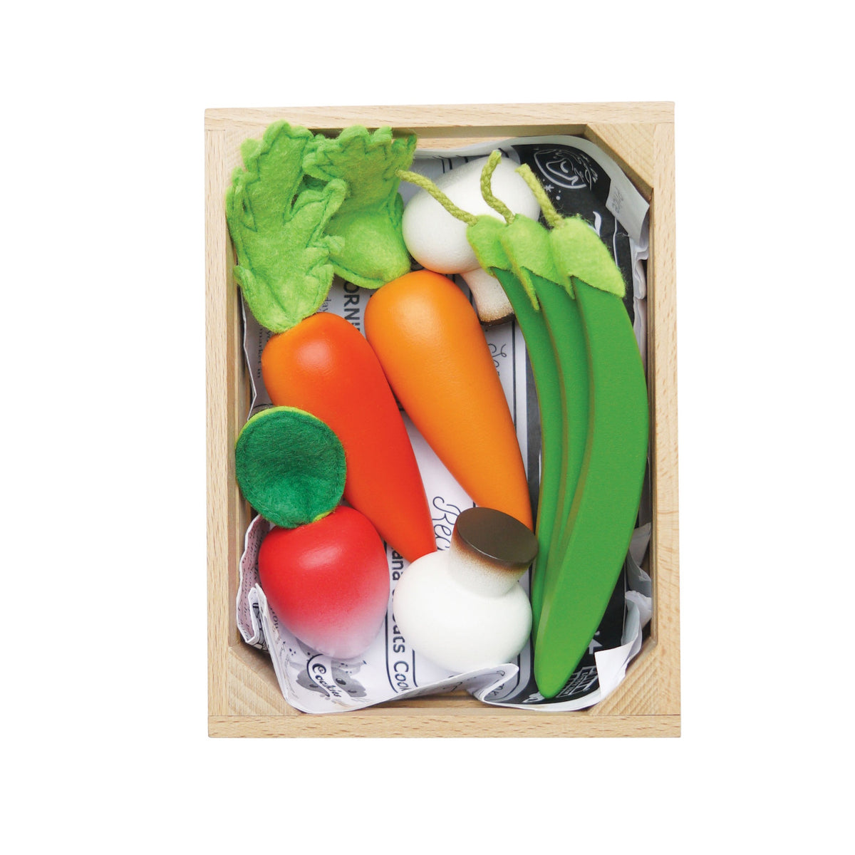 Top-down view of wooden play vegetables packed in a crate lined with newspaper.