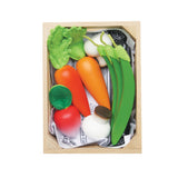 Top-down view of wooden play vegetables packed in a crate lined with newspaper.