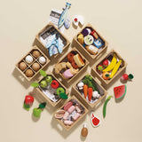 Wooden crates filled with toy play food like fruits, vegetables, fish, eggs, and bakery items.