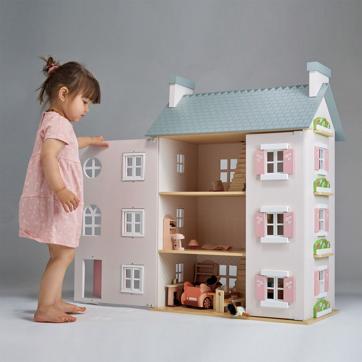 Child playing across the floors of the Heather Hall wooden dolls house