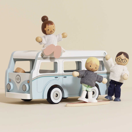 Wooden toy camper van with three small wooden figure dolls and a mini surfboard.