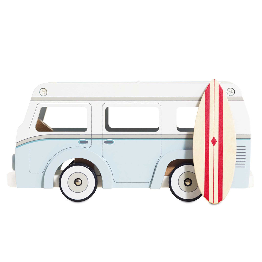 Toy vintage van in light blue with white details, featuring a detachable roof. A stylish surfboard with red stripes leans against the van, evoking a fun, coastal vibe.
