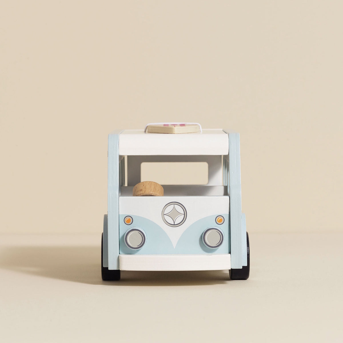 Front view of light blue and white wooden toy camper van with surfboard stored on top.