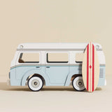 Light blue and white wooden toy camper van with a striped surfboard leaning against the side.